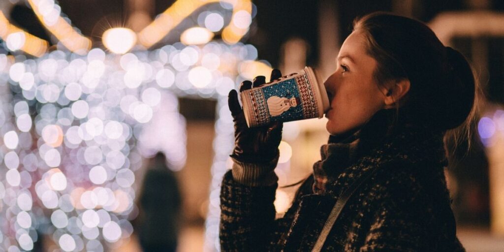 Woman drinking hot chocolate and looking at holiday lights
