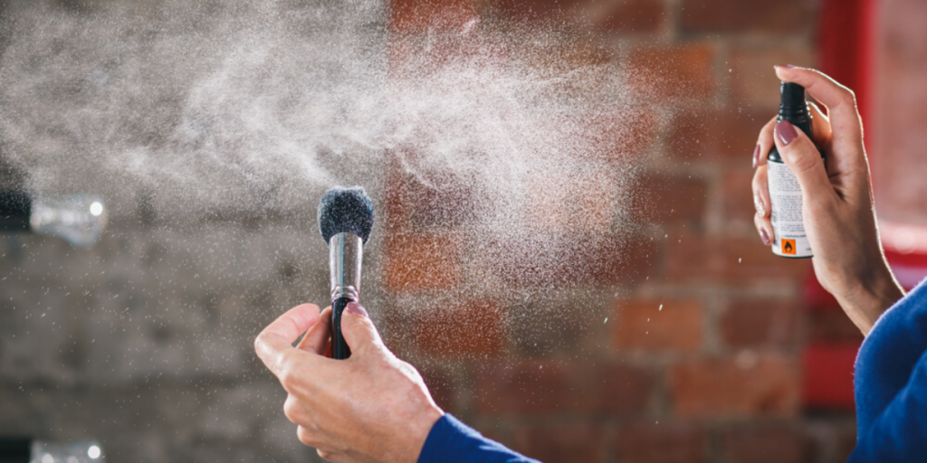 Woman spraying makup brush with disinfectant