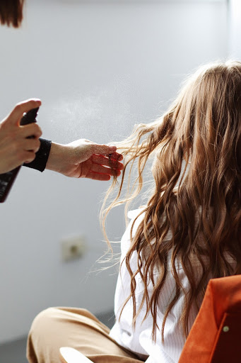 man hair spraying another woman's hair